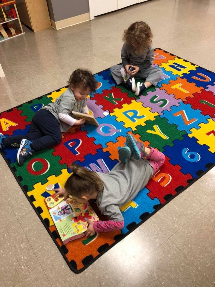 Three children playing on an alphabet rug