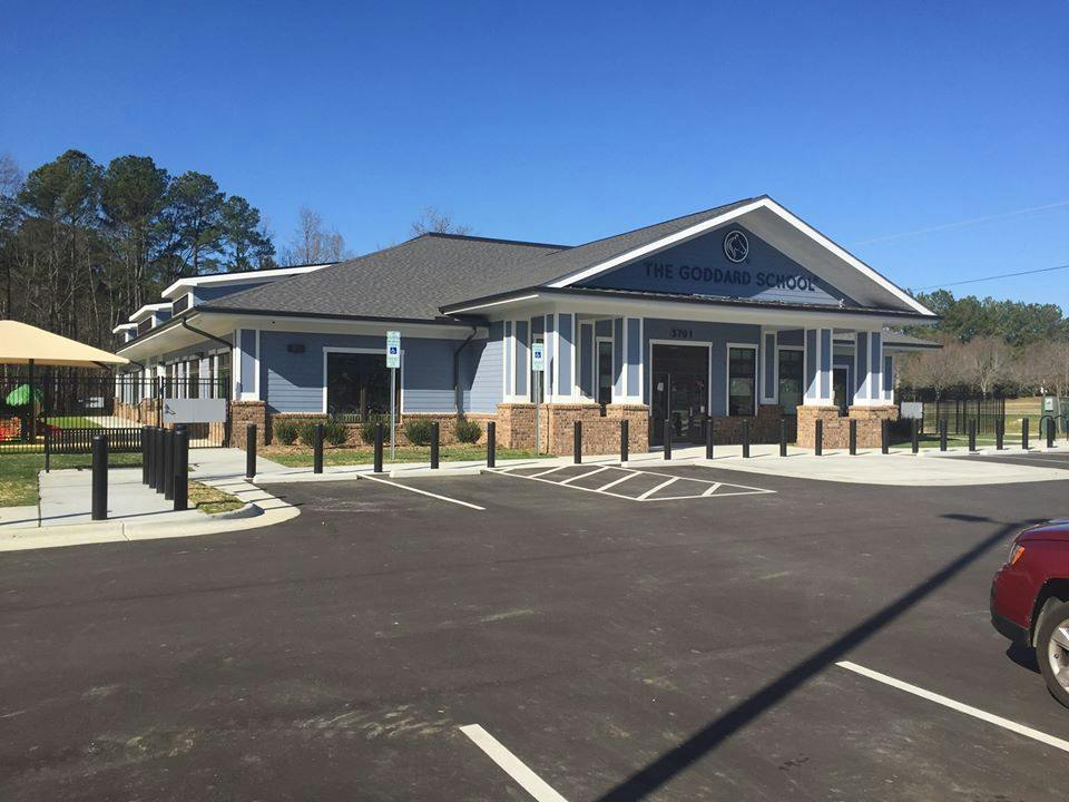 Building with blue siding and brick base, with a parking lot in front