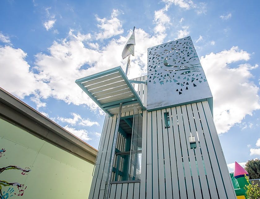 Play structure with a flag and decorative cutouts against a cloudy sky