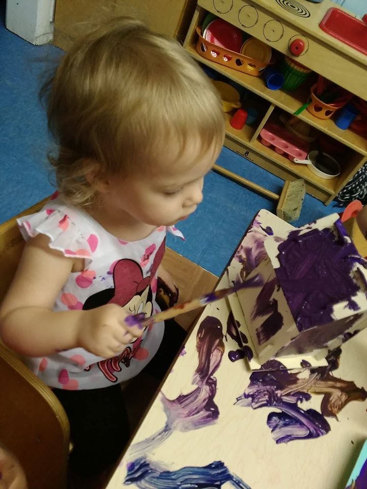 Child painting with purple paint
