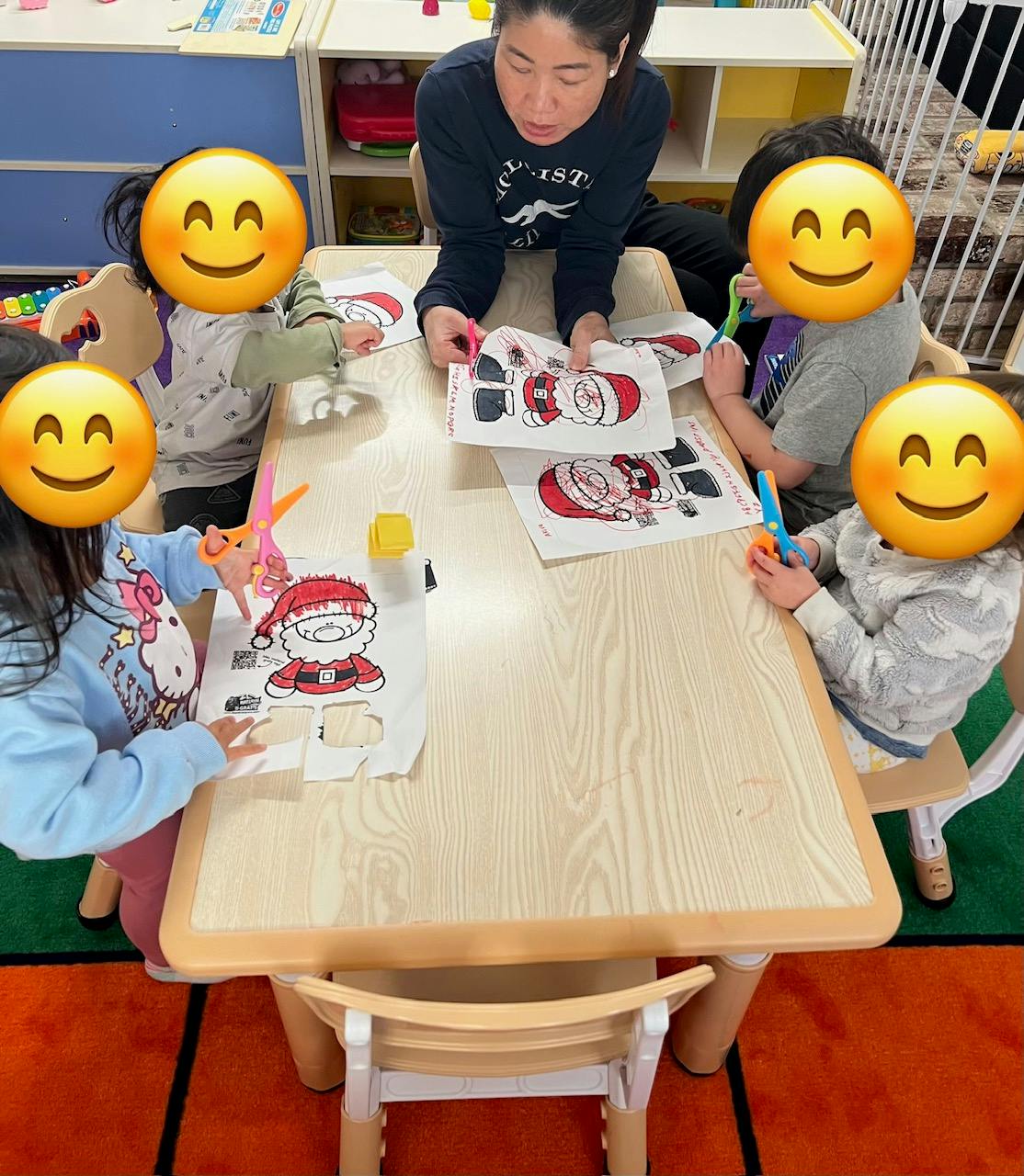 Adult and children at a table cutting out paper Santa Claus figures