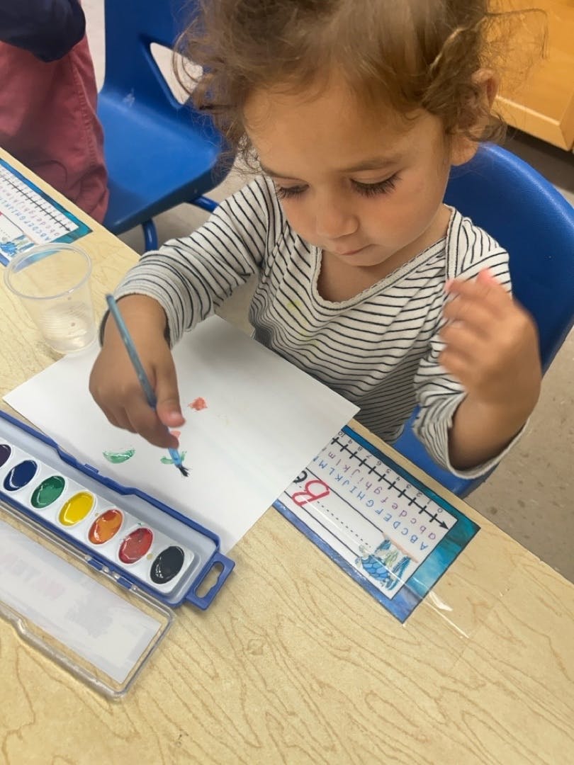 Child painting with watercolors at a desk