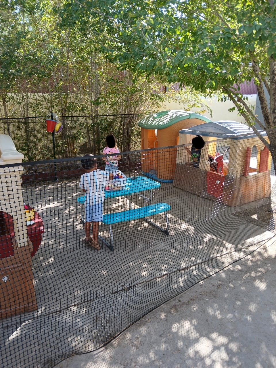 Children playing in an outdoor area with playhouses and a picnic table