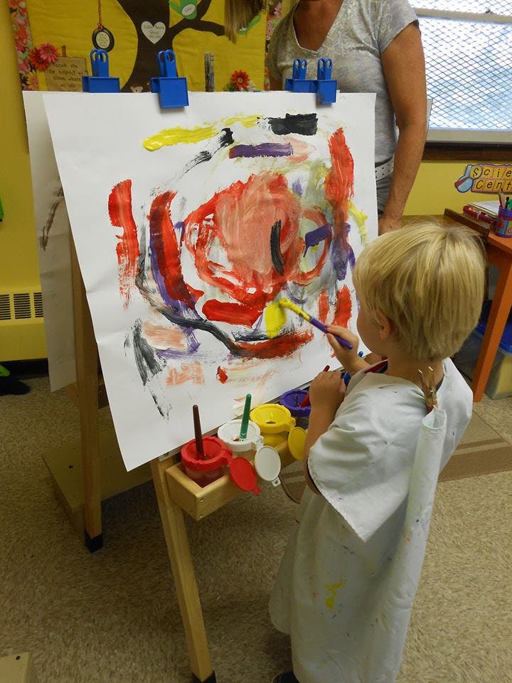 Child painting on an easel in a classroom
