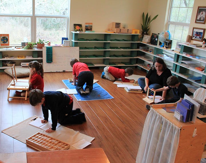 Adult and children working on floor in classroom