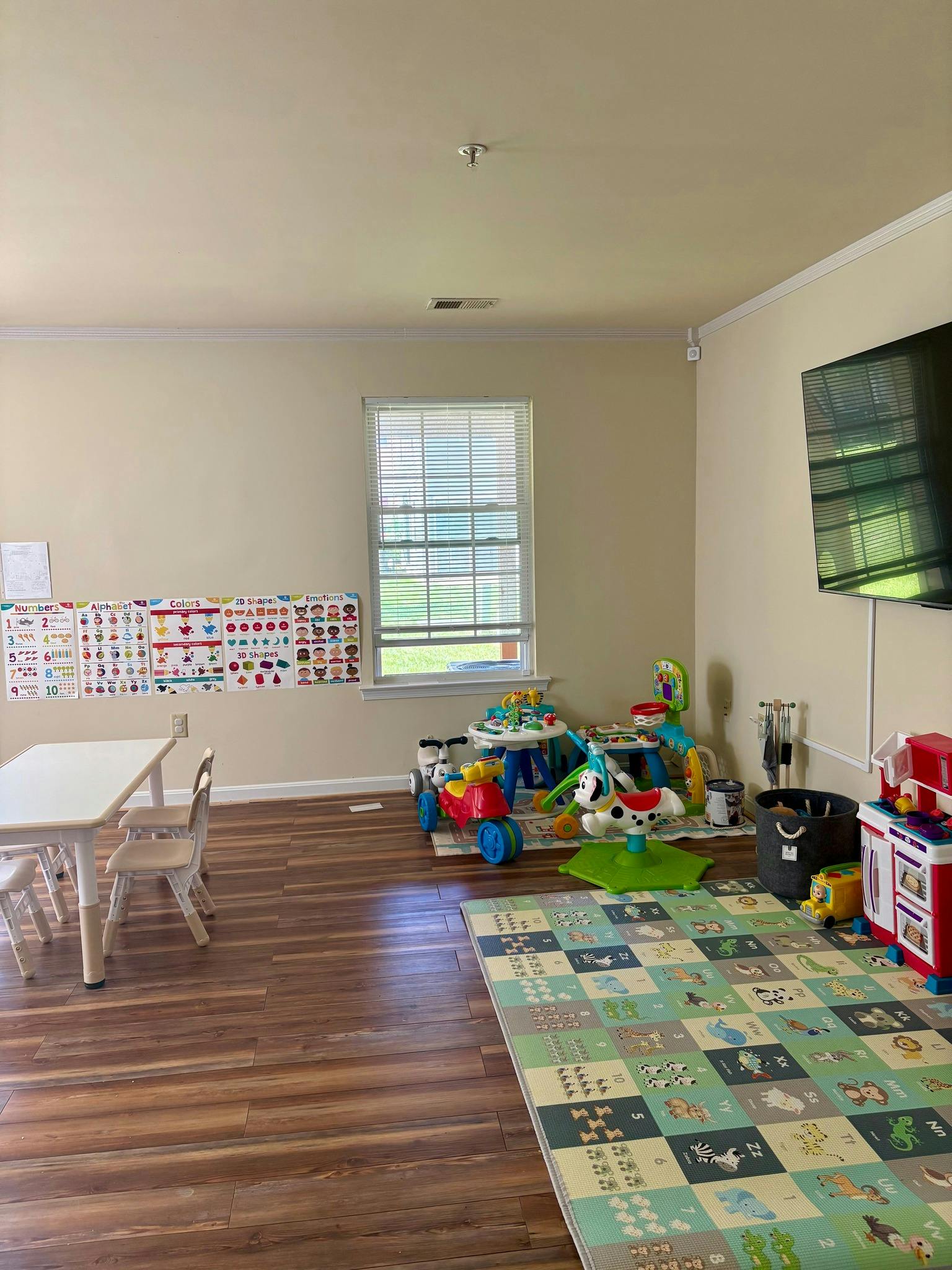 Playroom with a table and chairs, toys, and a patterned rug