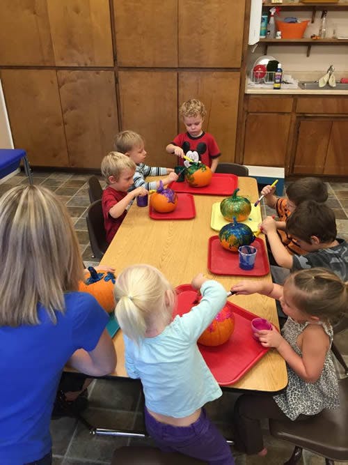 Children painting pumpkins at a table