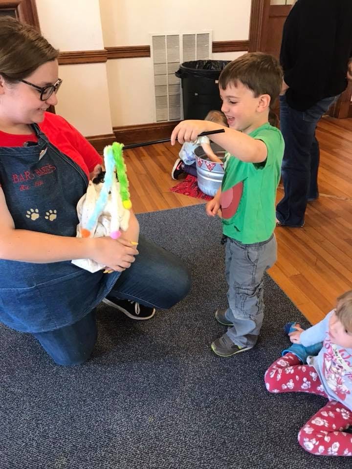 Person kneeling and holding an object while a child stands nearby