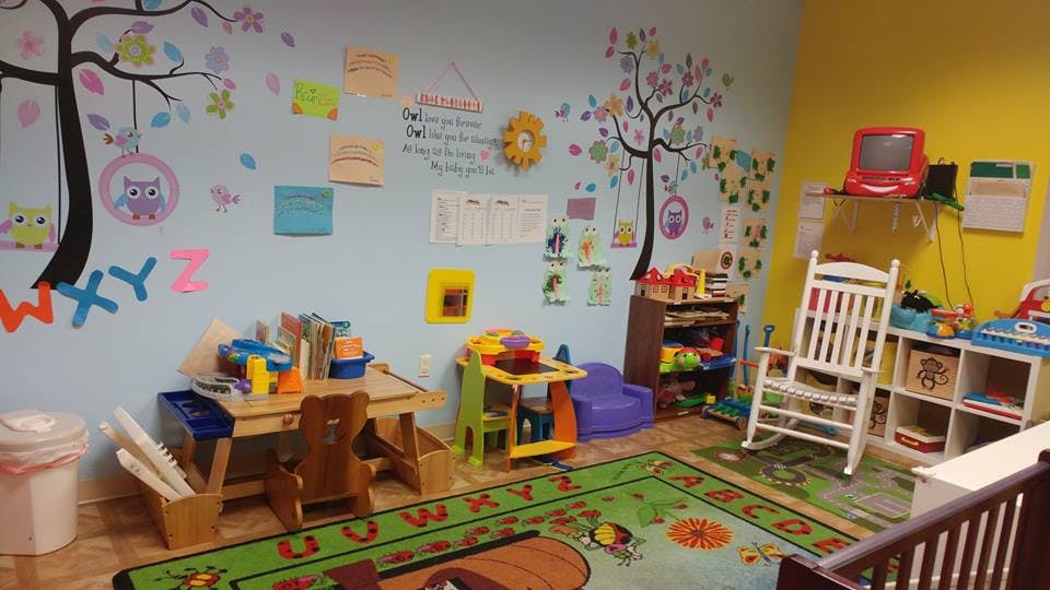 Playroom with colorful wall decorations, small tables, and a rocking chair