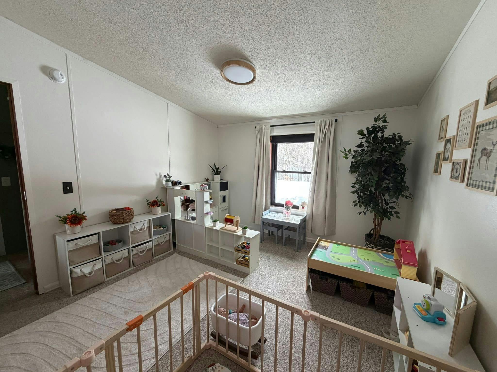 Playroom with storage units, toy kitchen, small table, and baby playpen