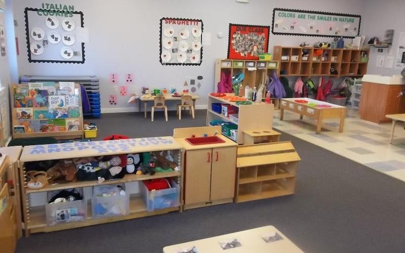 An empty early childhood classroom with shelves, tables, and decorations