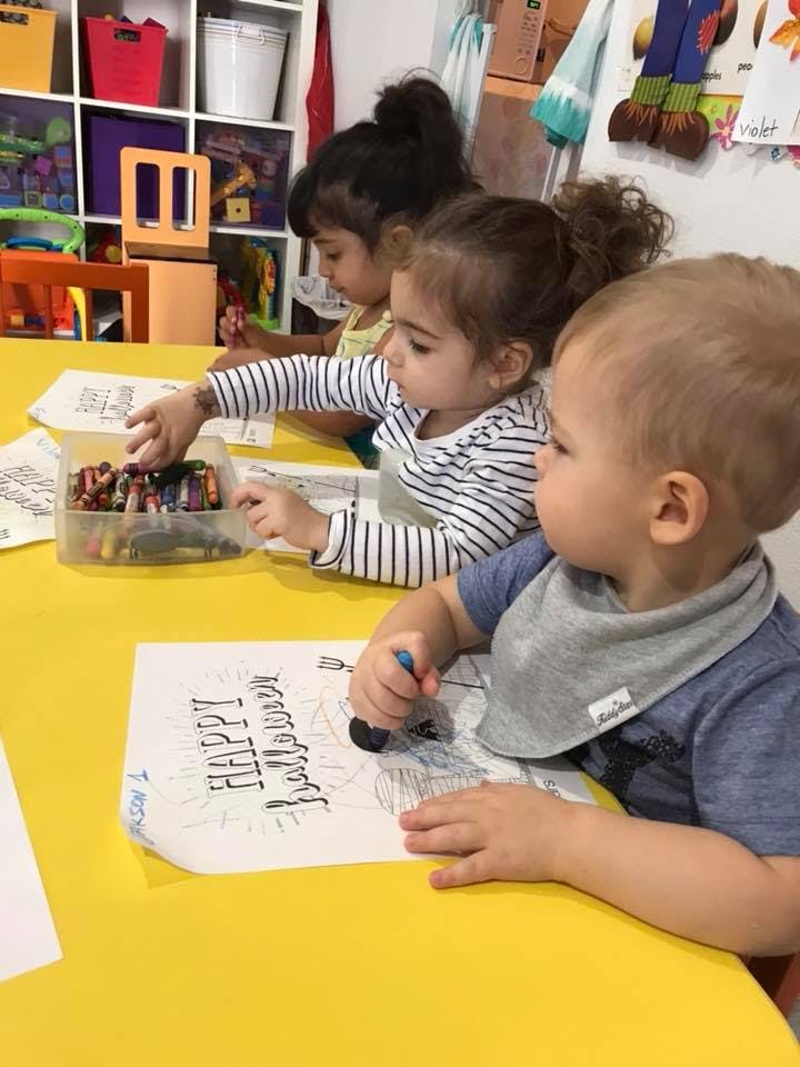 Three children drawing and coloring at a table
