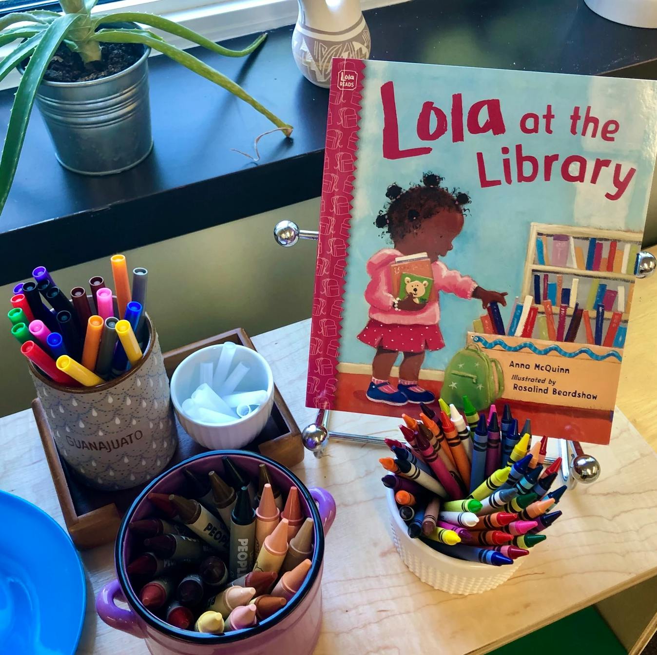 Children's book "Lola at the Library" with markers and crayons