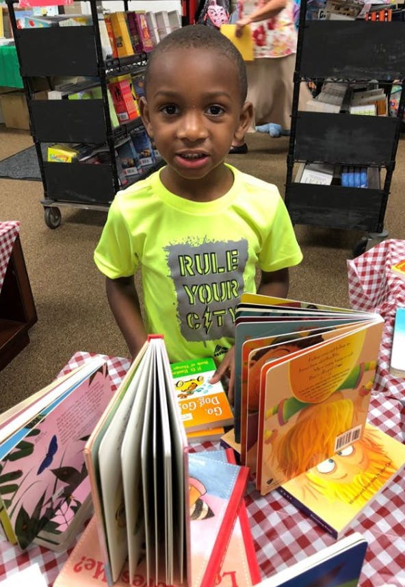 Child standing behind a table with open books