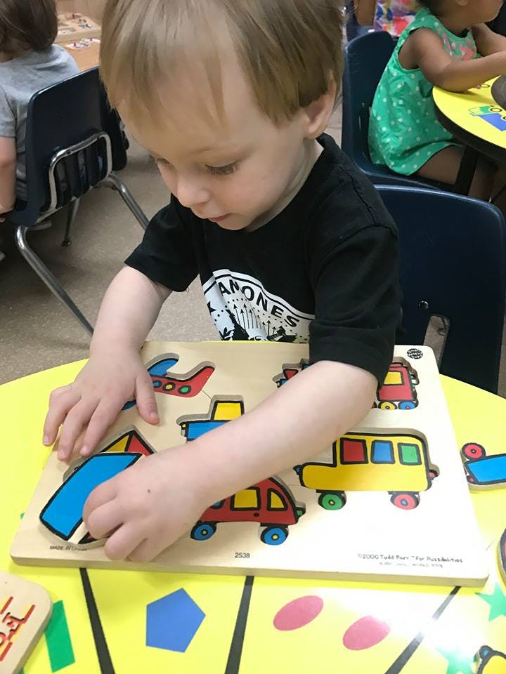 Child playing with a wooden vehicle puzzle