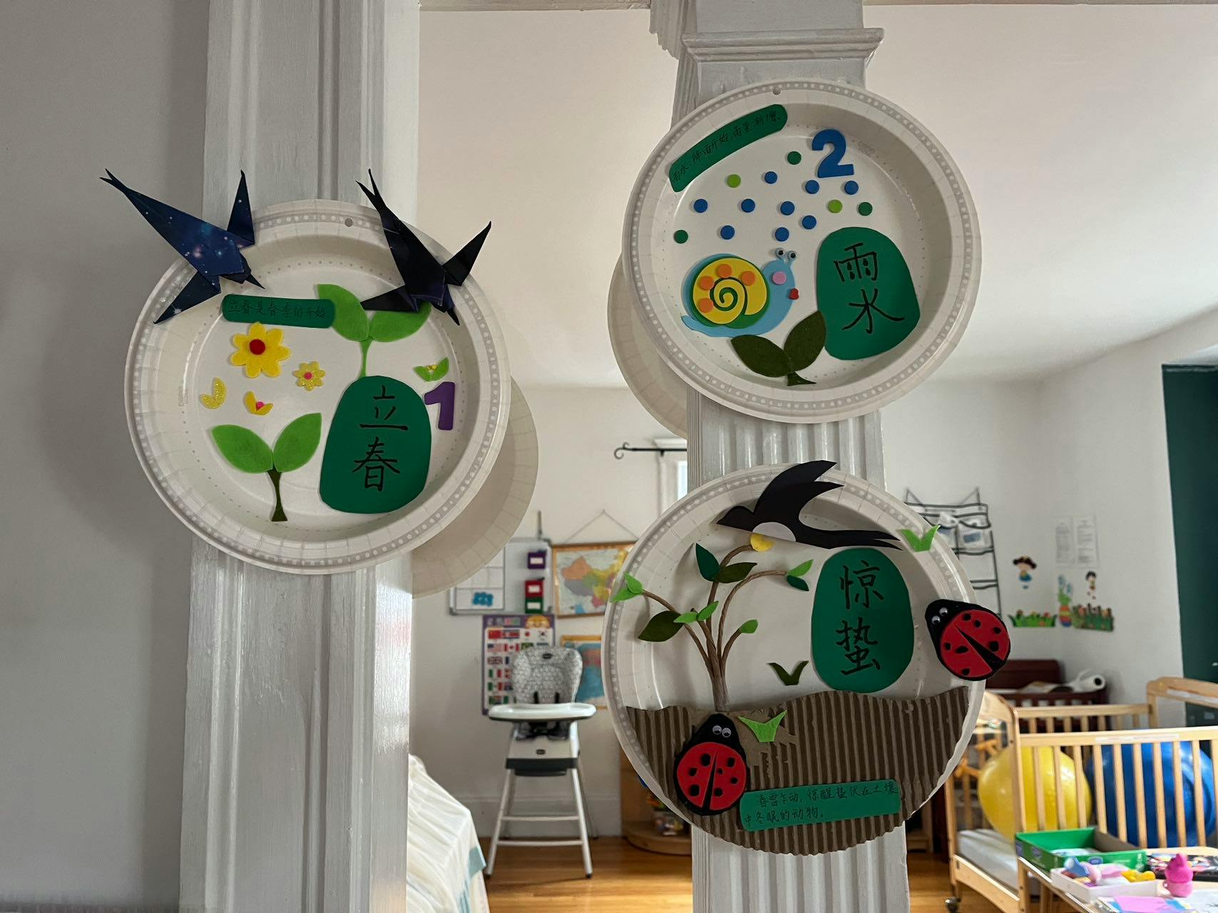 Three paper plates with nature-themed crafts, including plants, birds, and insects