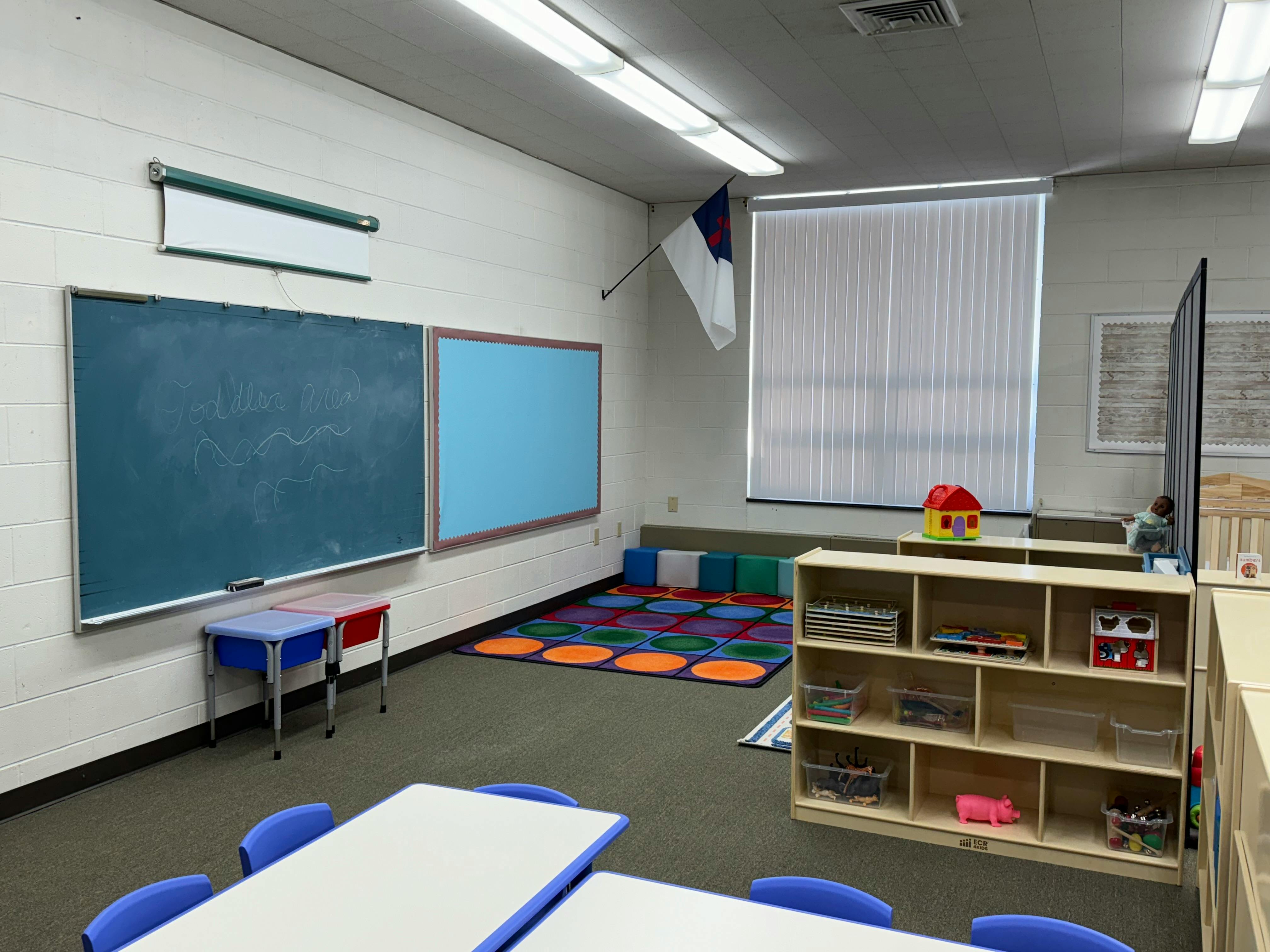 Empty classroom with blackboards, tables, and a colorful rug