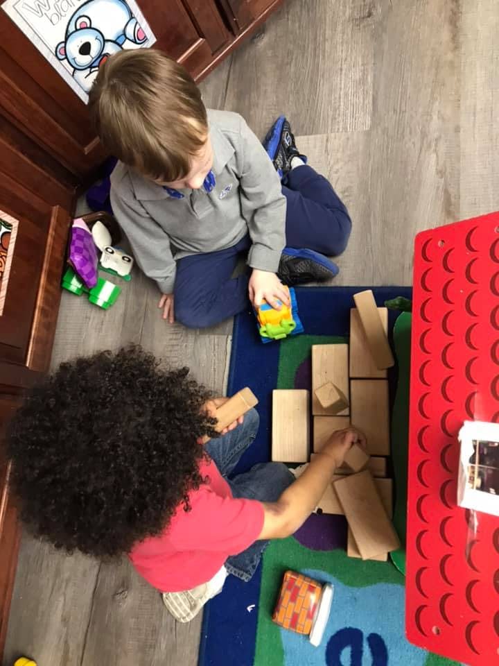 Two children playing with blocks on a rug