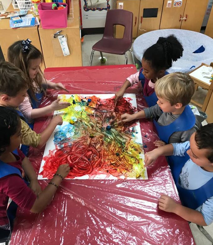 Children finger painting on a large canvas