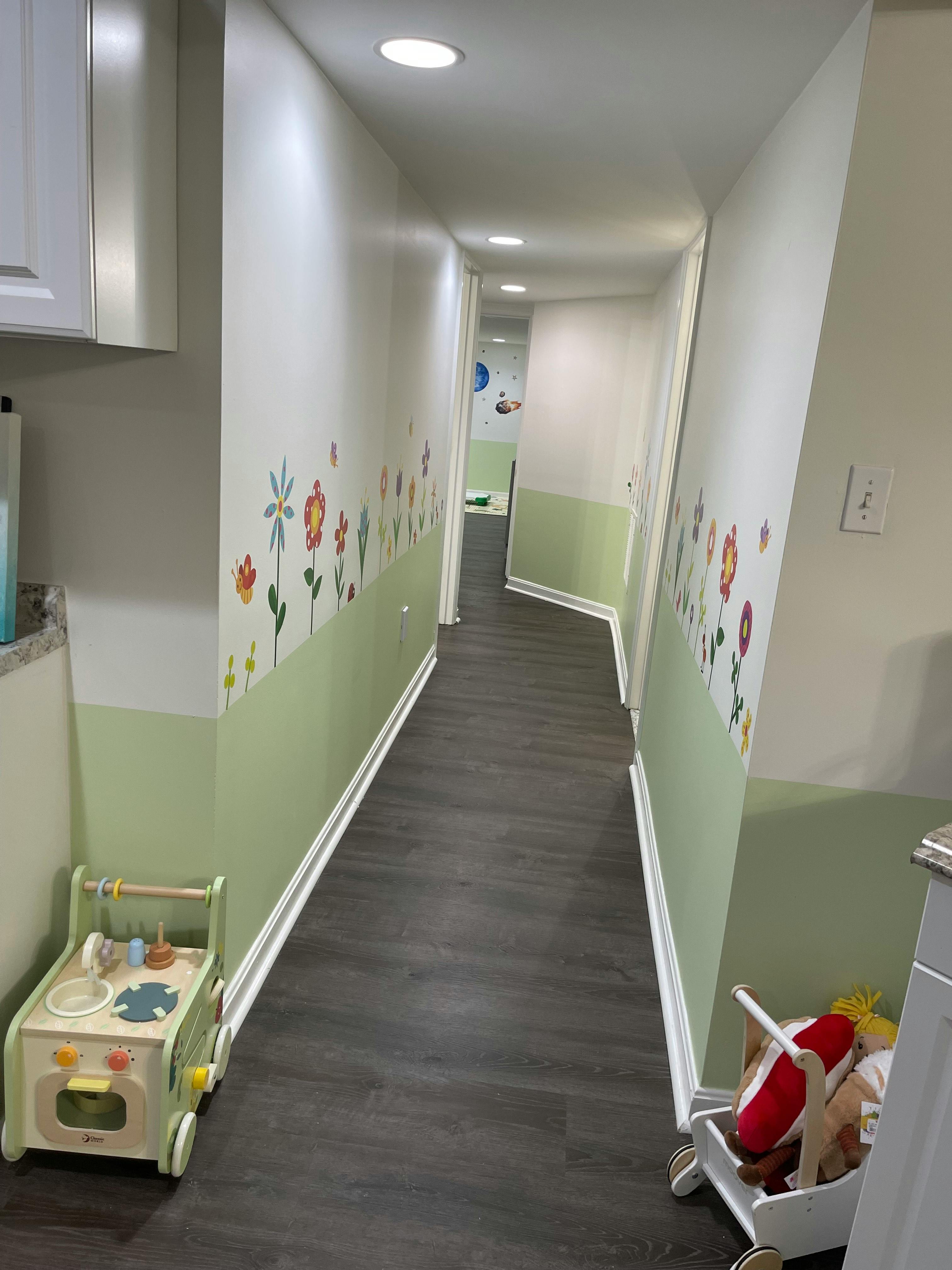 Hallway with light green walls and flower decals, toy walker on left