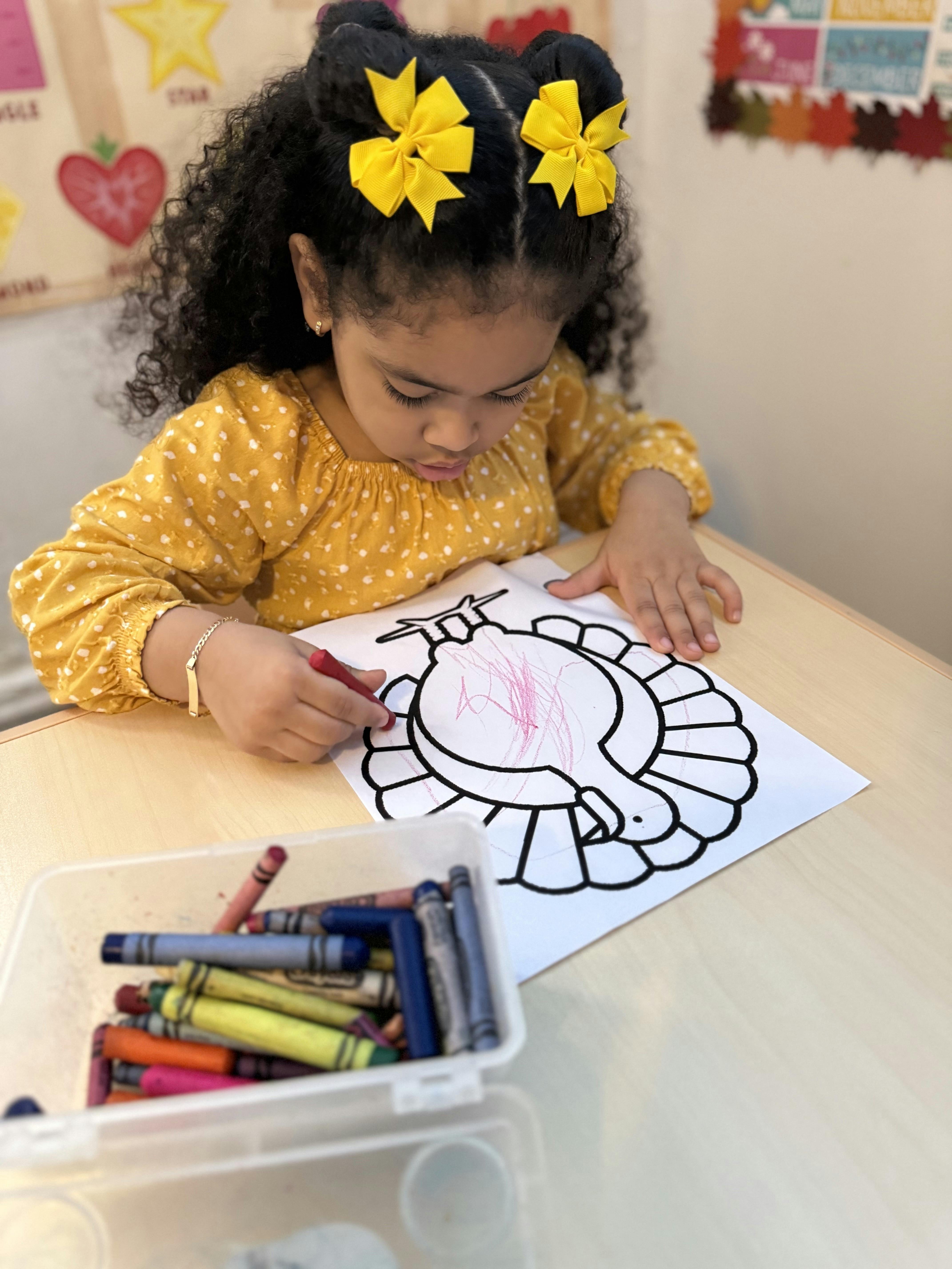 Child coloring a turkey drawing with a red crayon at a table