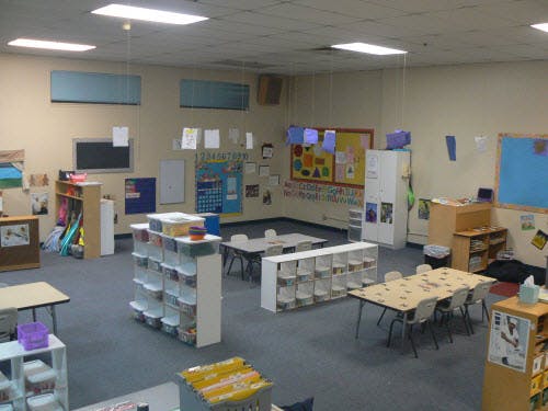 Empty classroom with tables, chairs, and storage units