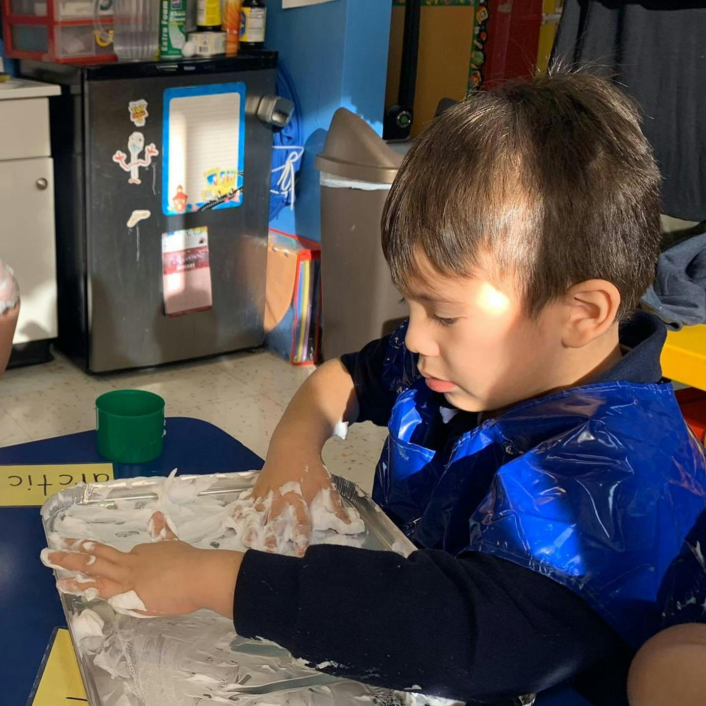 Child playing with shaving cream on a tray
