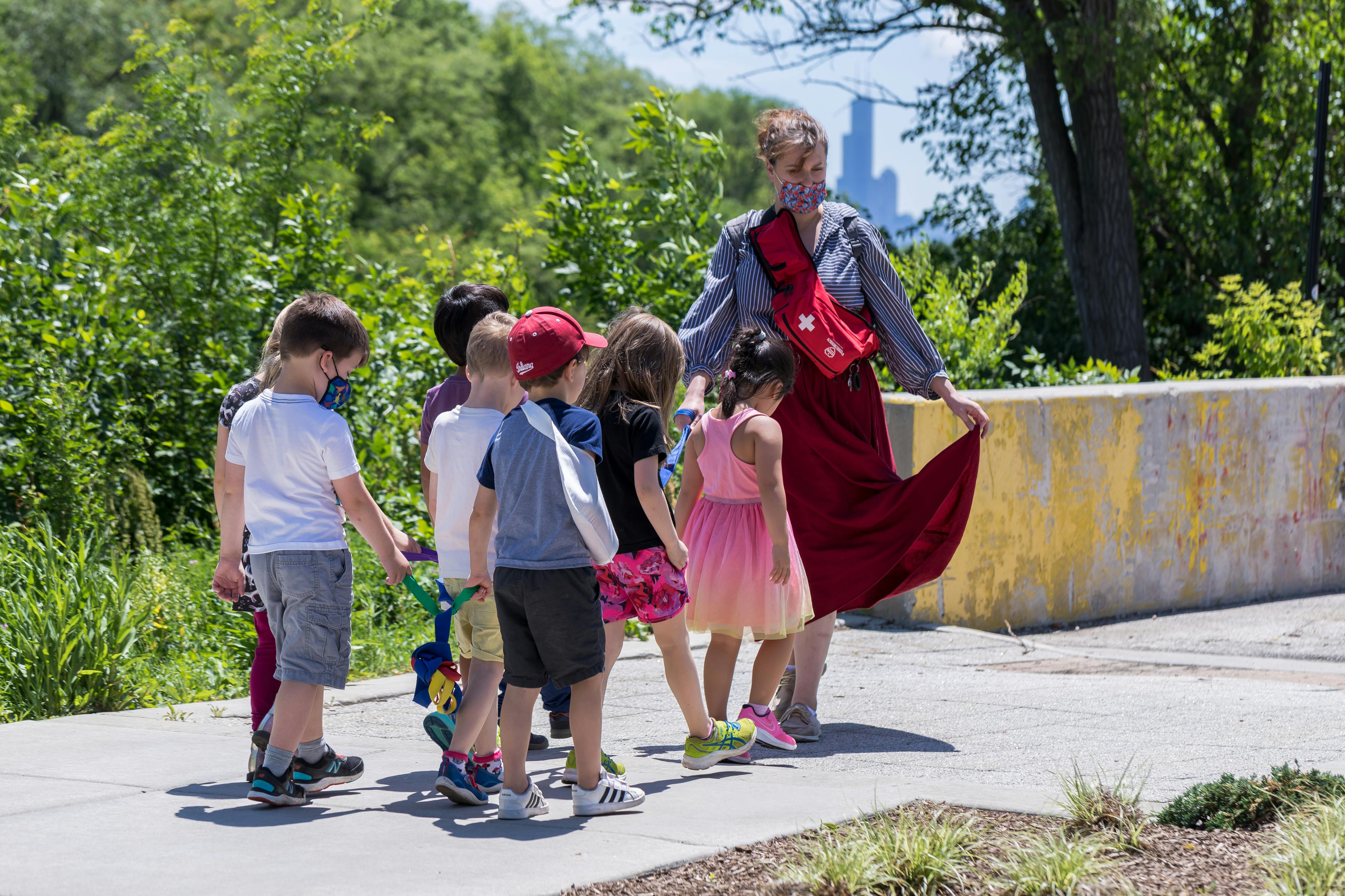 Person in red skirt walking with a group of children