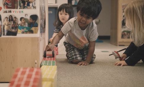 Child playing with toy car on floor with other children