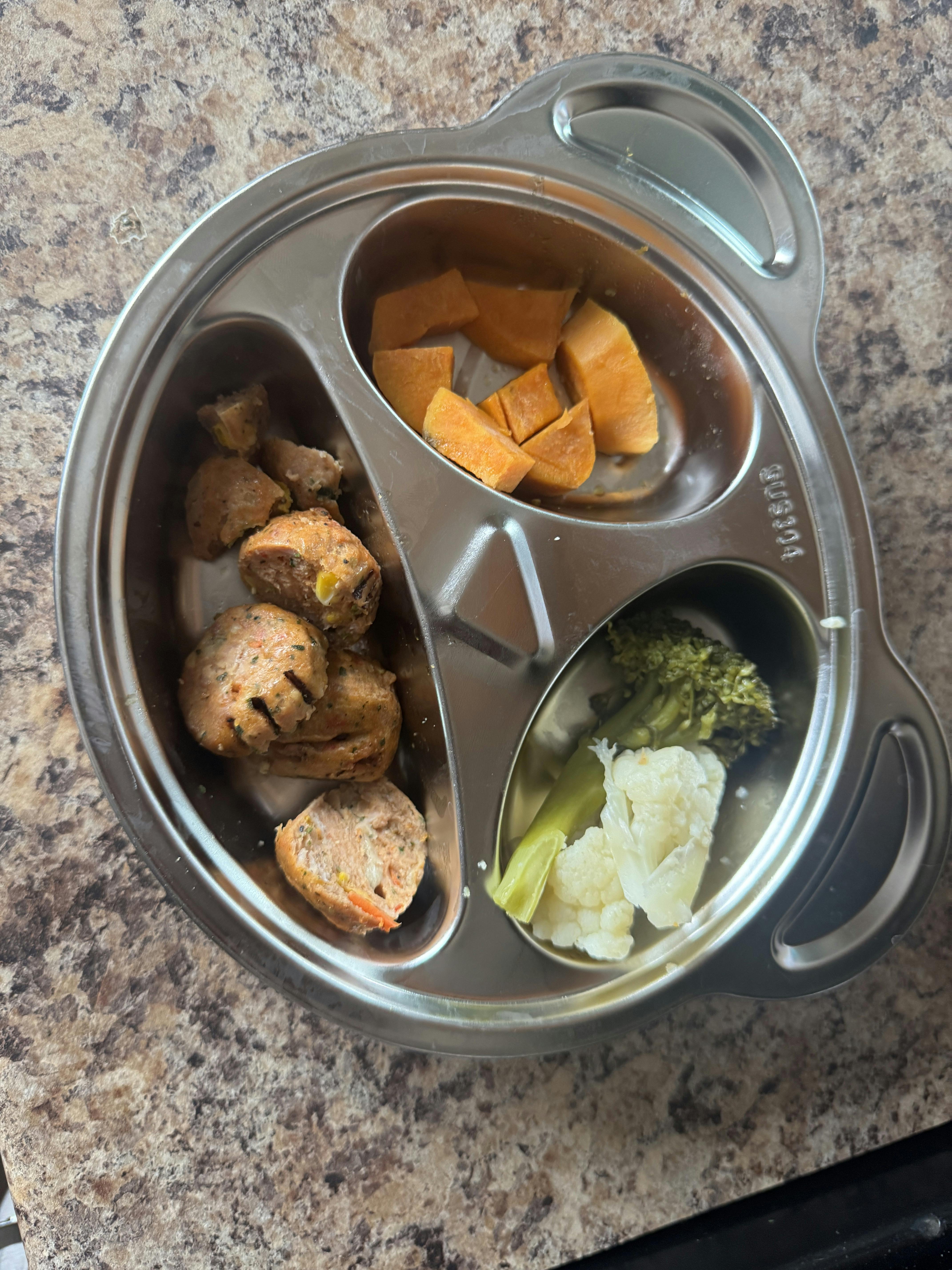 Split metal tray containing cut sausage, cooked sweet potato, and vegetables