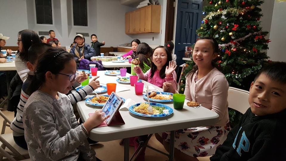 Children sitting at tables with plates of food