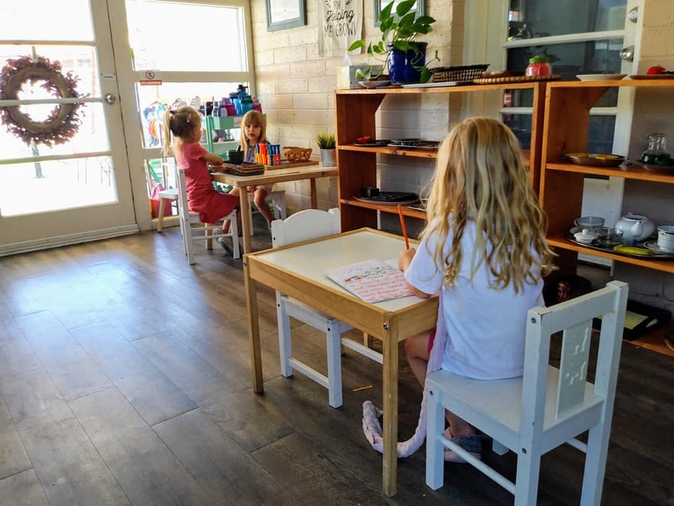 Three children sitting at small desks in a classroom