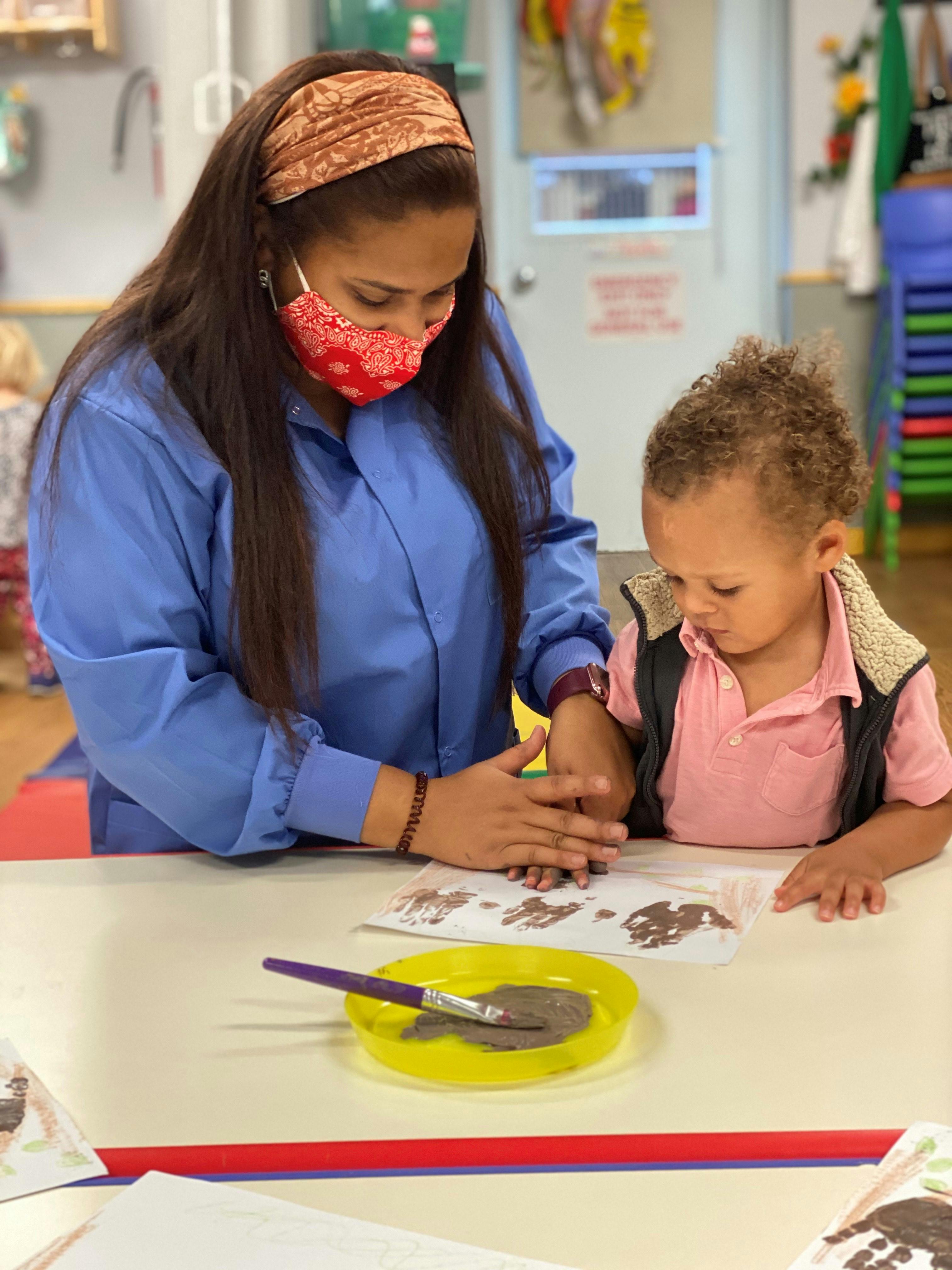 Person and child doing an art activity in a classroom