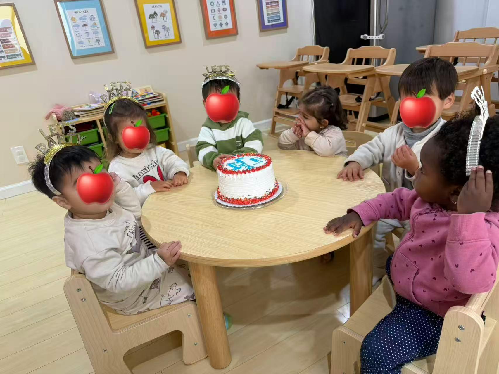 Five young children at a small table with a birthday cake