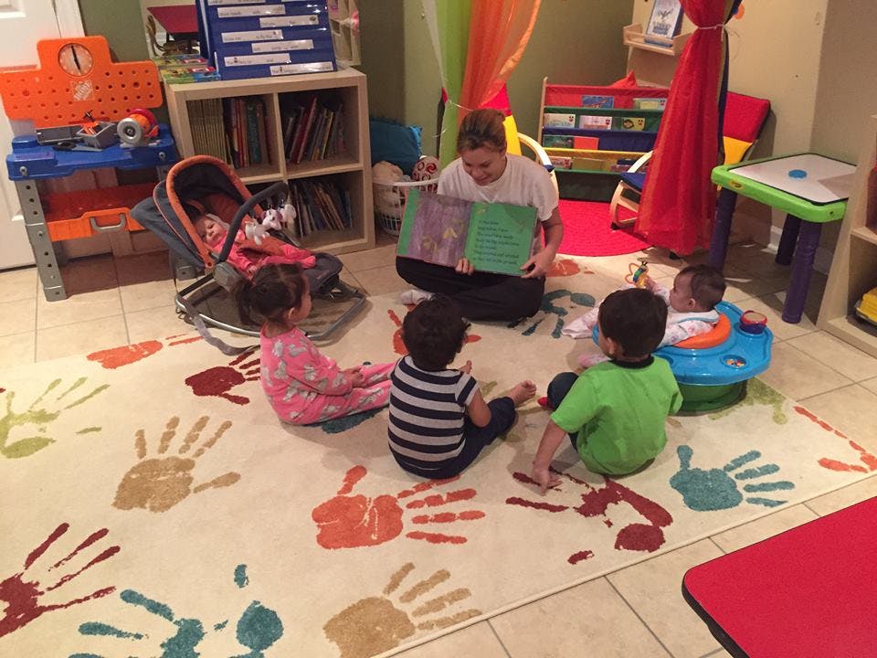 Person reading a book to several children in a classroom