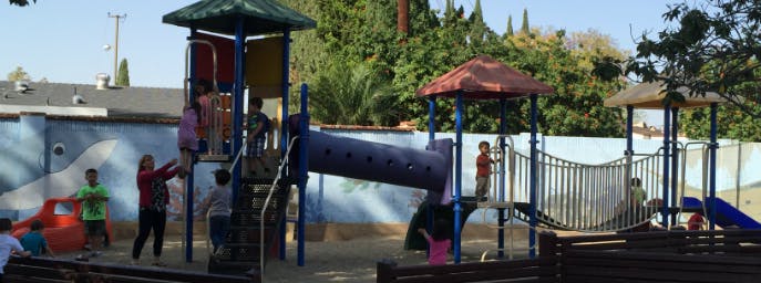 Children playing on a playground structure with slides and climbing areas