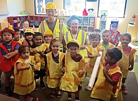 Adults and children in construction vests and hard hats
