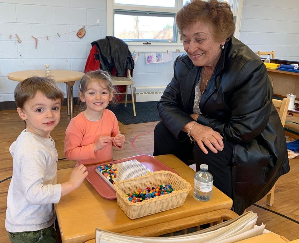 Two children and an adult at a table with colorful beads