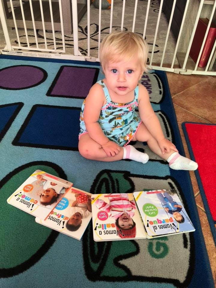 Child sitting on a rug with several books spread out in front