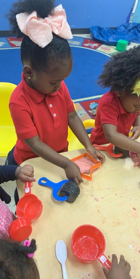 Child playing with playdough and cookie cutters at a table