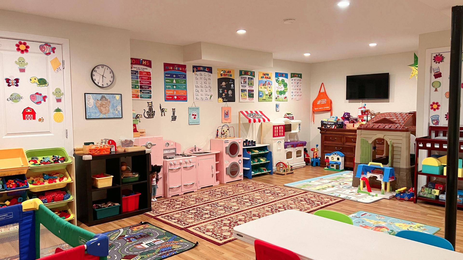 Playroom with toys, rugs, and educational posters on the walls