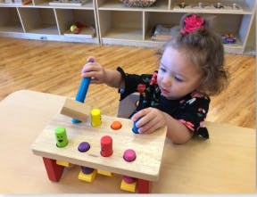 Child playing with a wooden pounding toy