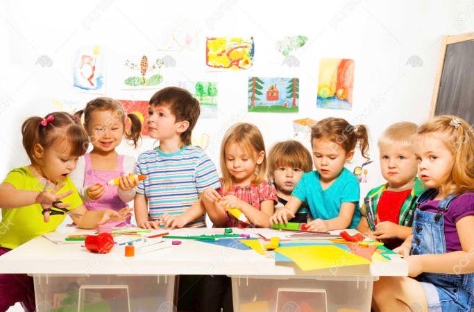 Group of children working on crafts at a table in a classroom