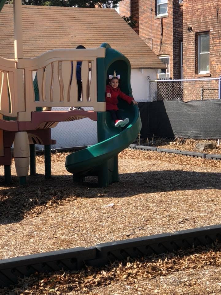 Child in a red shirt on a green playground slide