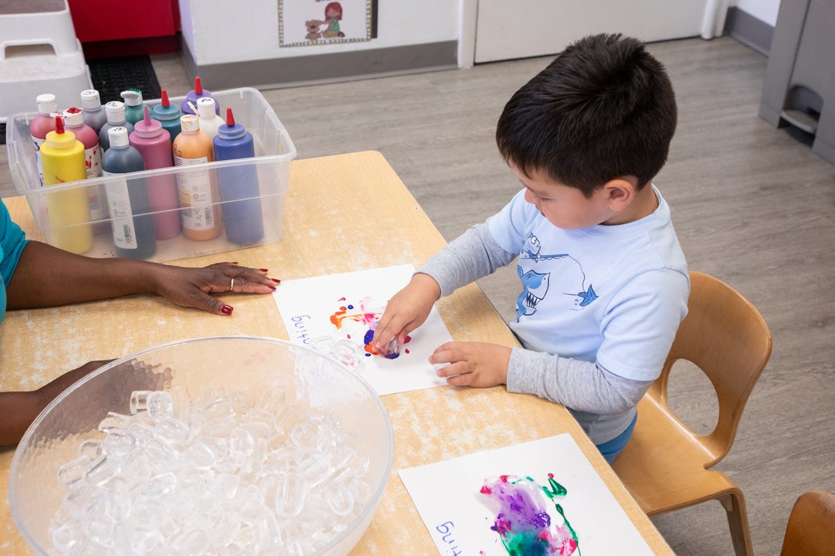 Child finger painting at a table