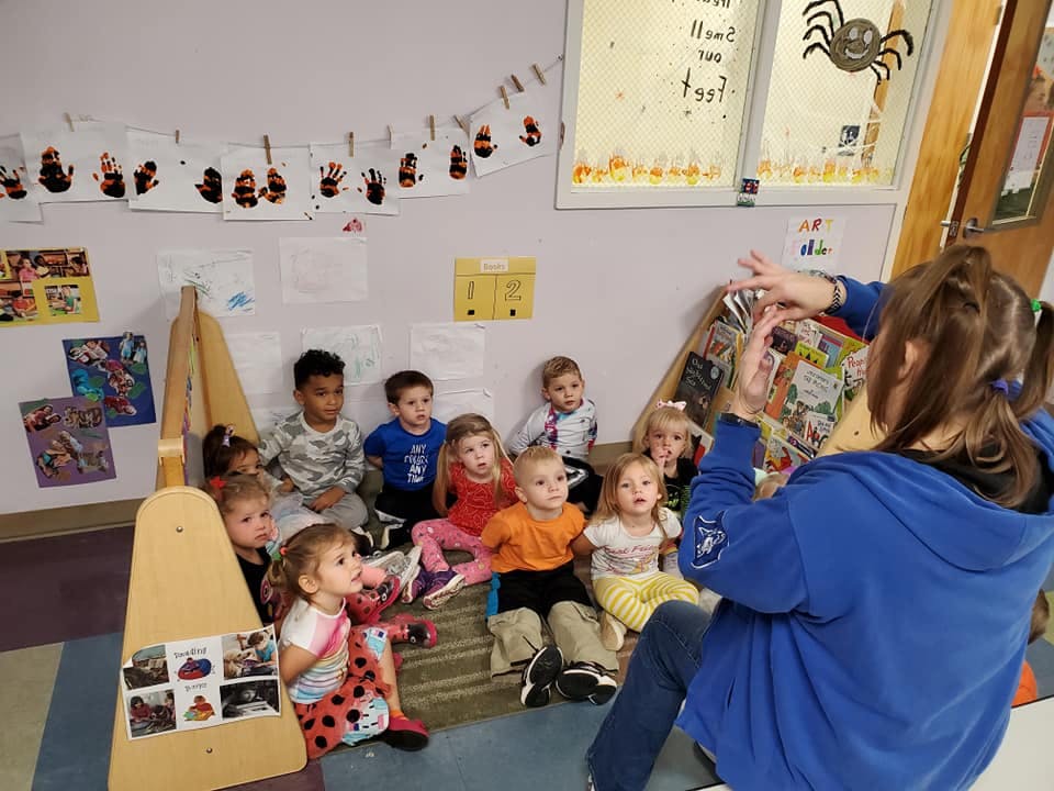 Person reading to a group of children in a classroom