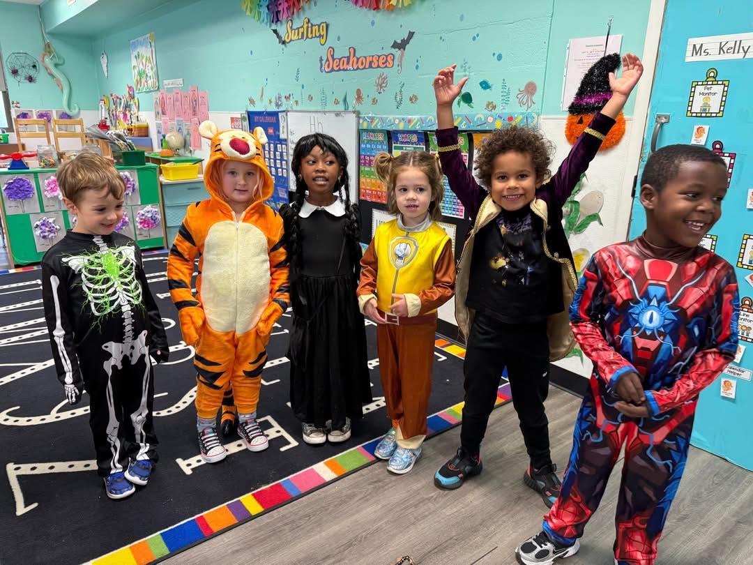 Six children in costumes standing in a classroom