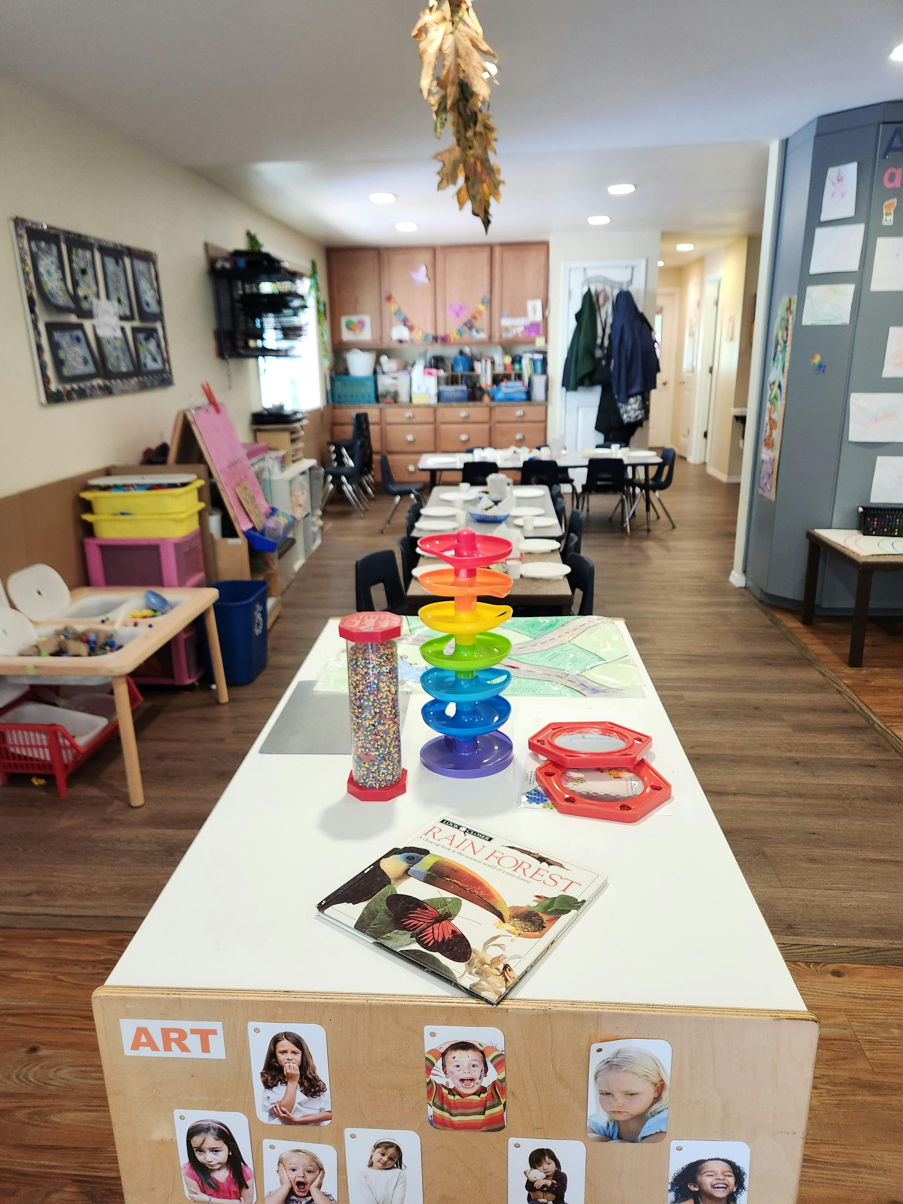 Classroom with tables, chairs, and children's artwork on the wall