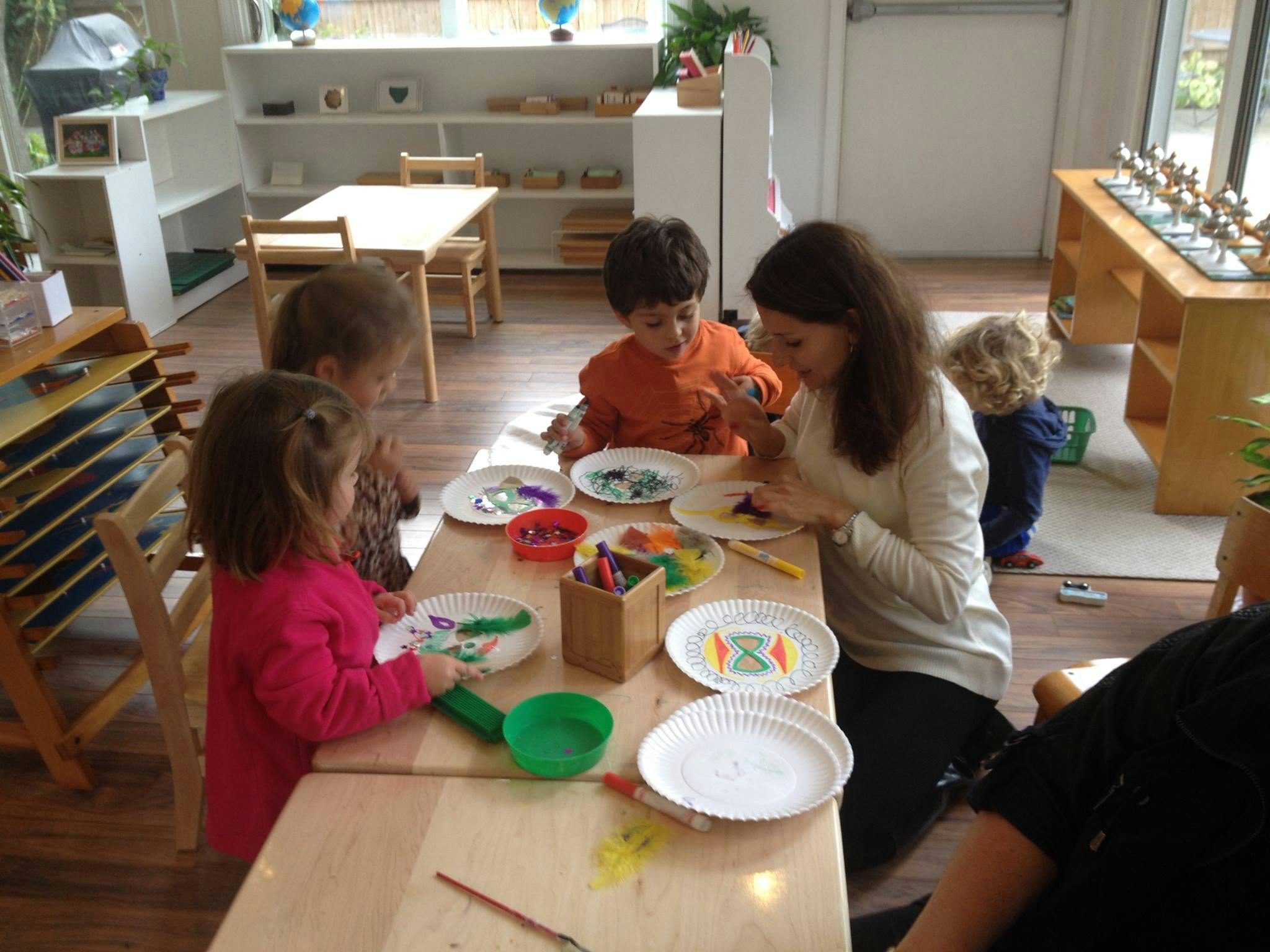Adult and children doing crafts at a table in a classroom