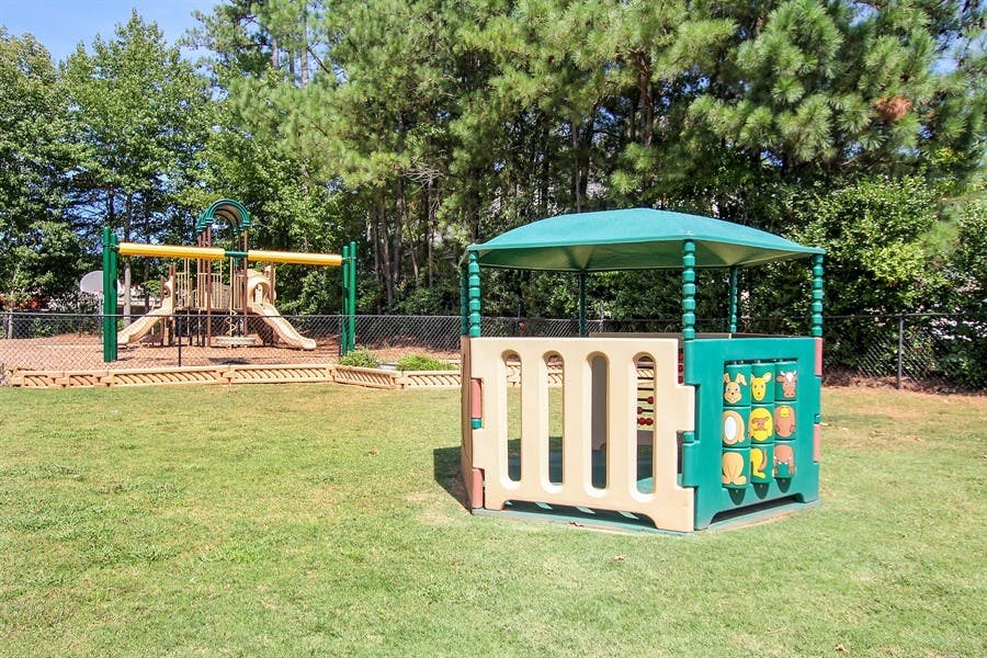 Playground with a small playhouse and a larger structure with slides and swings